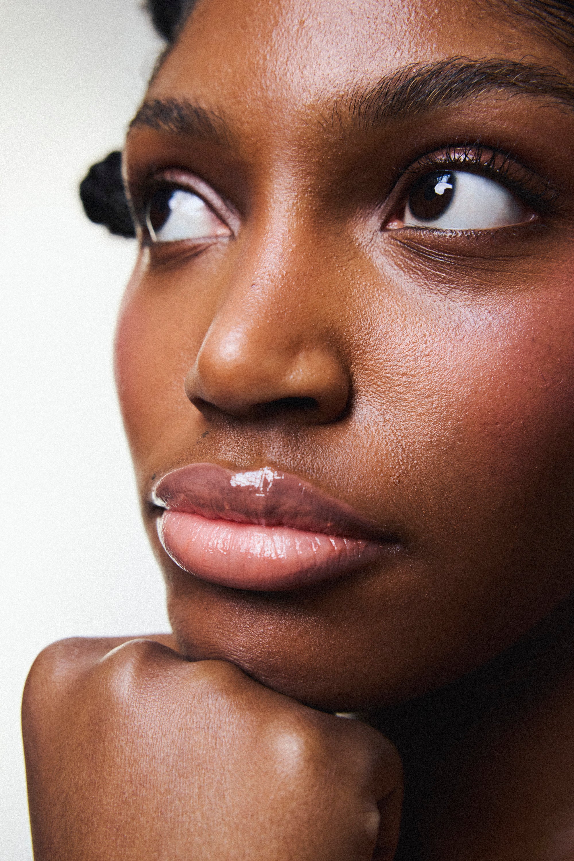 Application du gloss à lèvres éclat nourrissant Melayci, teinte Candy rosée, sur une femme à la peau noire.
