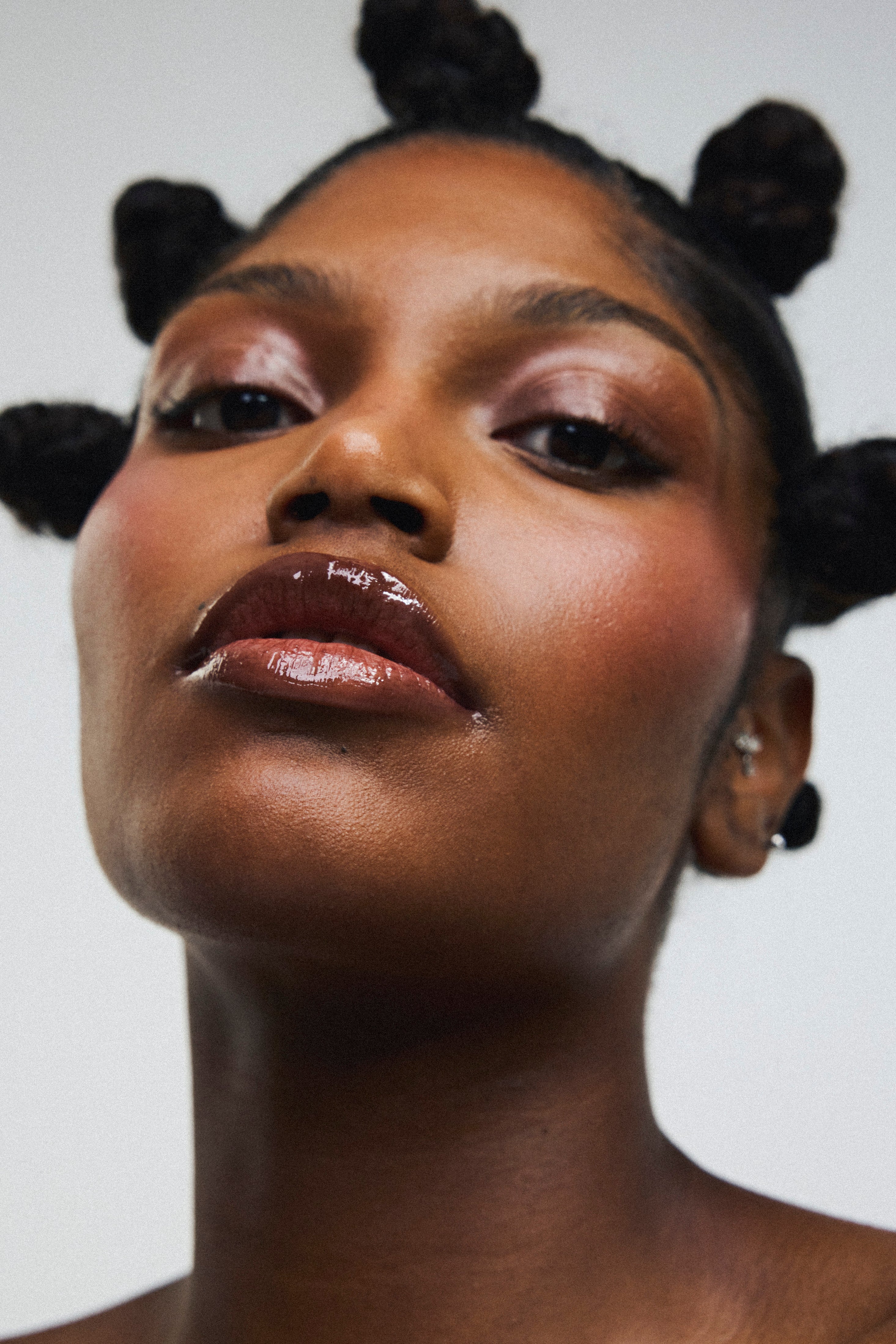 Gloss à lèvres teinte Espresso marron Melayci porté par un modèle femme à la peau métissée, nourrissant et glossy.