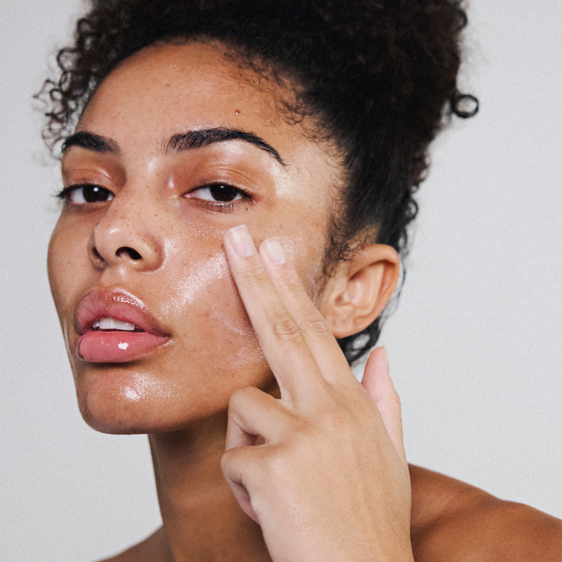 Application de l’huile visage modulable Melayci montrant sa texture crème sur la peau.
