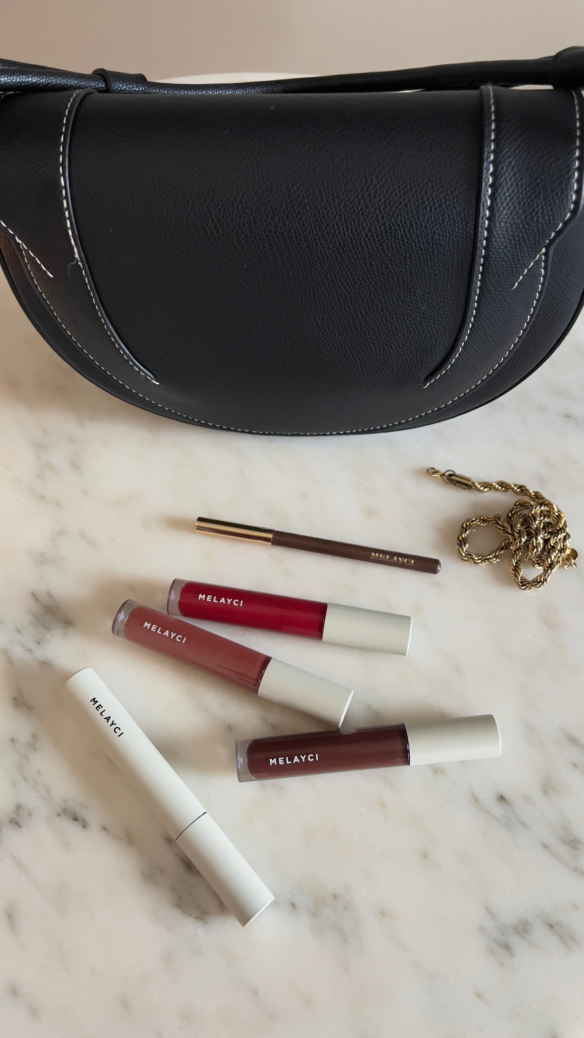 Photo lifestyle montrant un sac à main et le mascara, le gloss et le crayon à lèvres Melayci.
